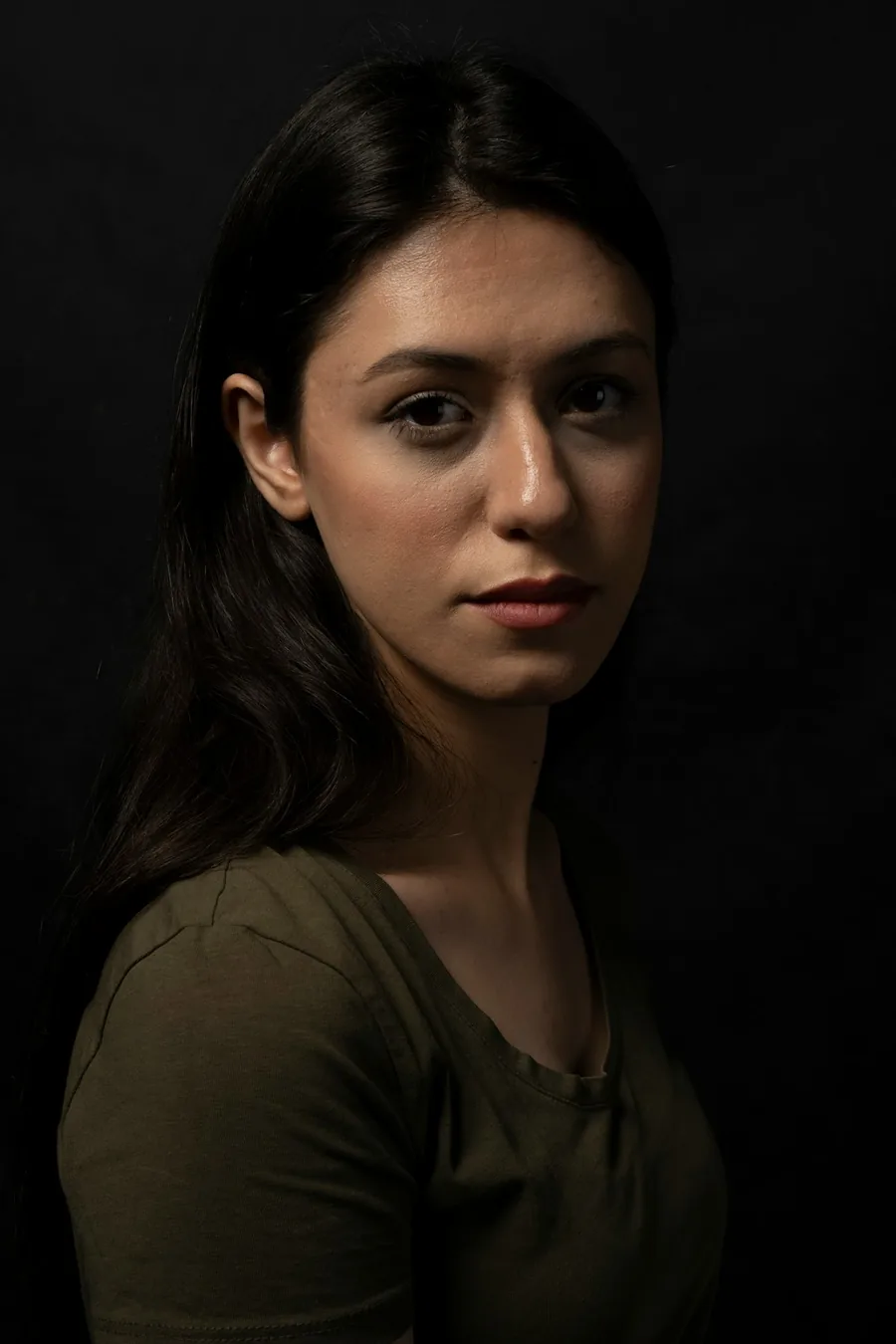 Portrait de studio sur fond sombre avec lumière latérale dessinant le visage